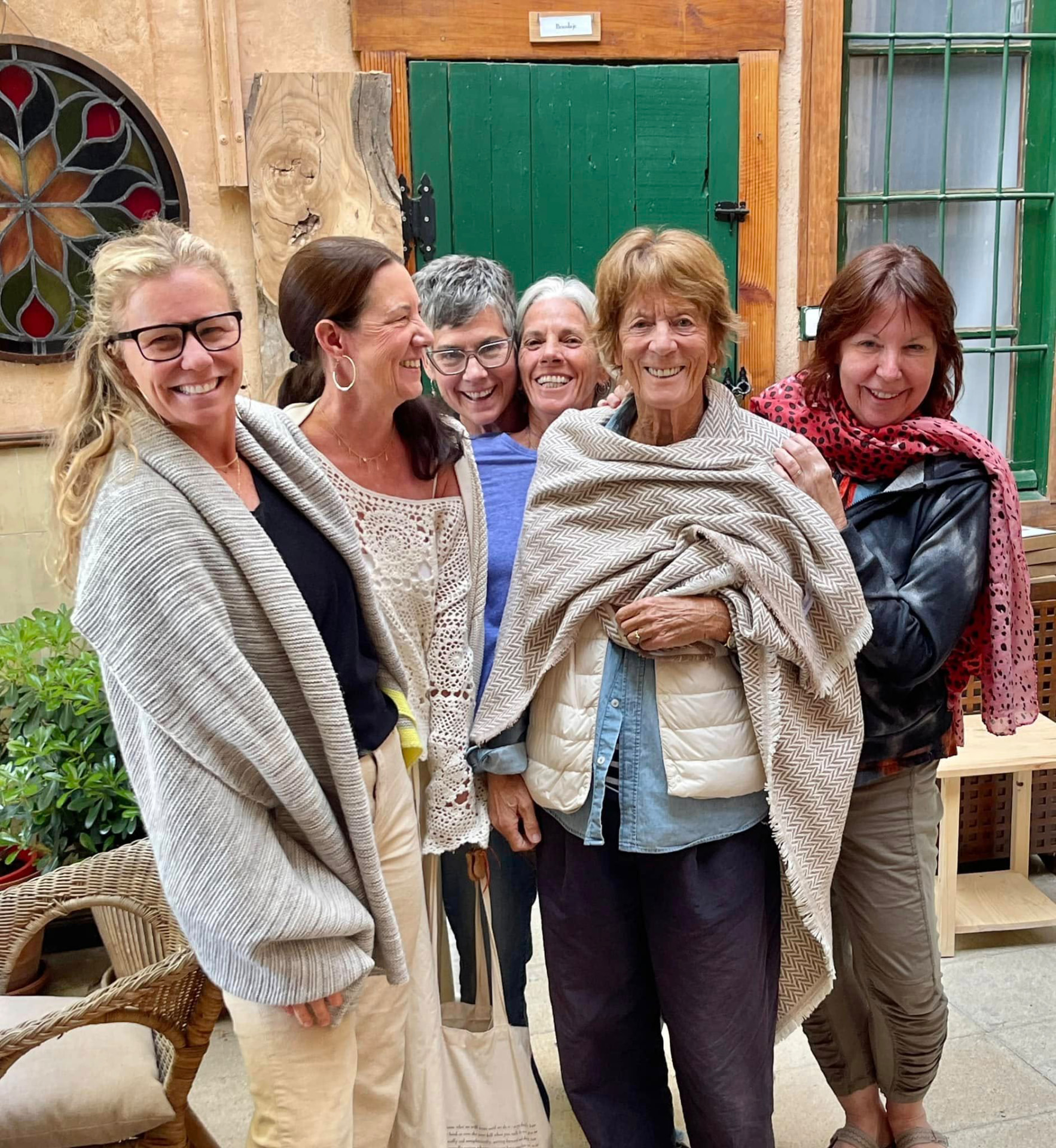 Rosalind Brackenbury laughing among a group of women writers in a courtyard, wrapped in a woven shawl