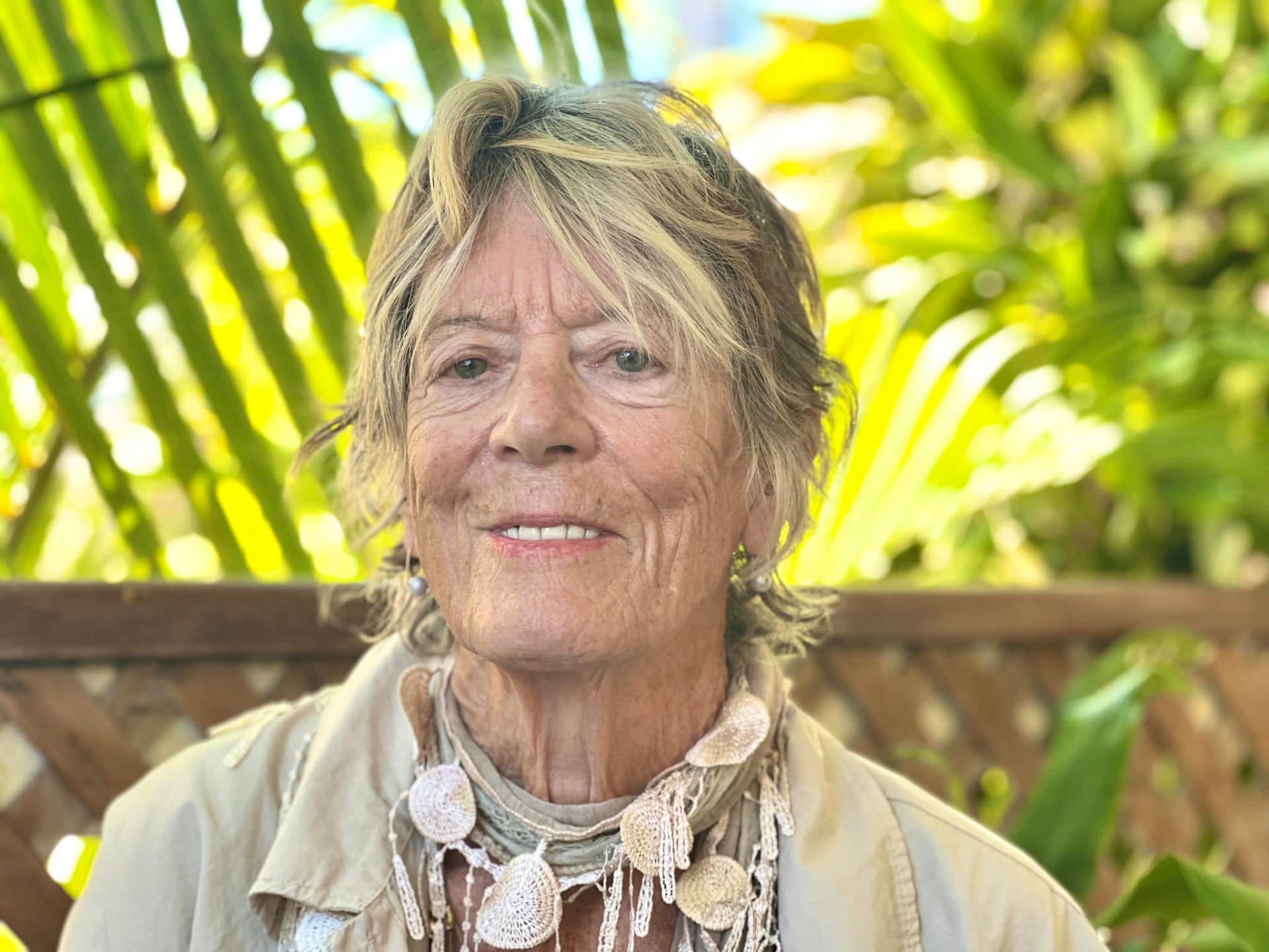 Rosalind Brackenbury smiling in sunlight in front of palm fronds